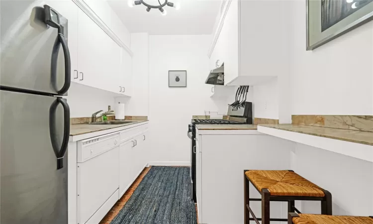 Kitchen with sink, dark wood-type flooring, extractor fan, white appliances, and white cabinets