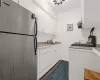 Kitchen with stainless steel refrigerator, white cabinetry, dishwasher, sink, and dark hardwood / wood-style flooring