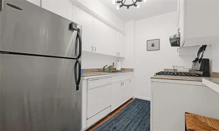 Kitchen with stainless steel refrigerator, white cabinetry, dishwasher, sink, and dark hardwood / wood-style flooring