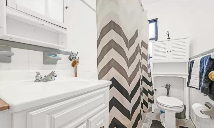 Bathroom with sink, tile walls, and toilet