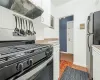 Kitchen with white cabinetry, refrigerator, extractor fan, and stainless steel gas range