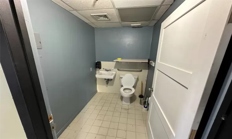 Bathroom with tile patterned floors, toilet, a drop ceiling, and sink