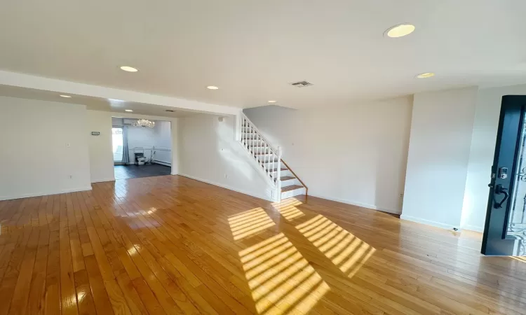 Unfurnished living room with wood-type flooring and a notable chandelier