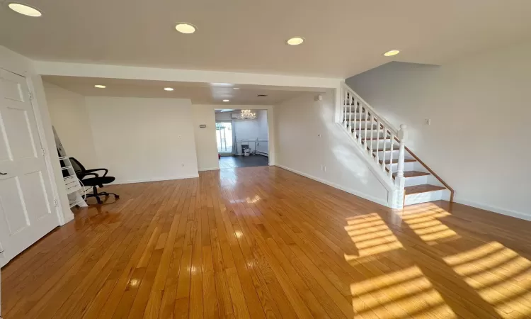 Unfurnished living room featuring hardwood / wood-style floors and an inviting chandelier