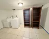 Clothes washing area with washing machine and clothes dryer and light tile patterned floors