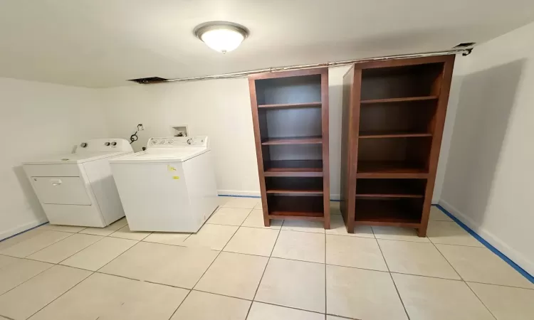 Clothes washing area with washing machine and clothes dryer and light tile patterned floors