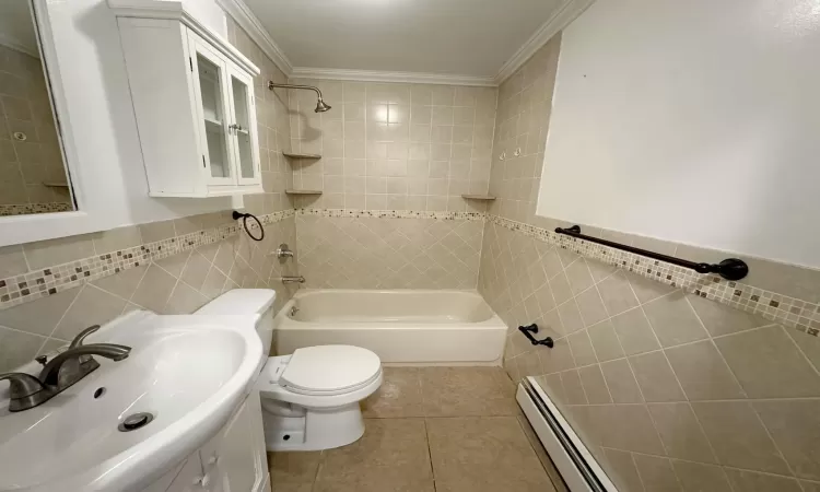 Full bathroom featuring tile patterned floors, crown molding, baseboard heating, and tile walls