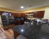 Kitchen featuring kitchen peninsula, appliances with stainless steel finishes, light wood-type flooring, backsplash, and dark stone countertops