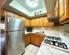 Kitchen featuring ventilation hood, sink, light tile patterned floors, gas range gas stove, and stainless steel refrigerator