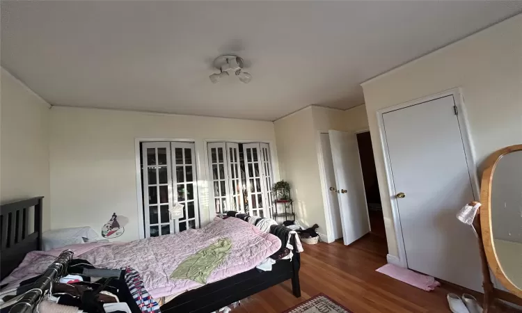 Bedroom with french doors, hardwood / wood-style flooring, and ornamental molding