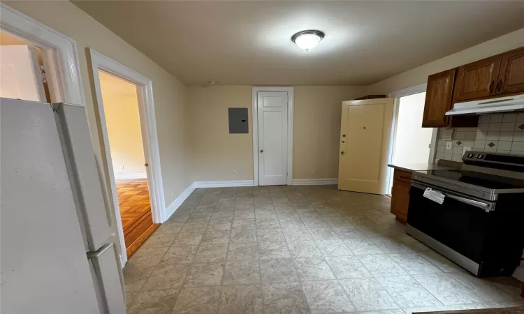 Kitchen with white refrigerator, electric panel, light hardwood / wood-style floors, decorative backsplash, and range