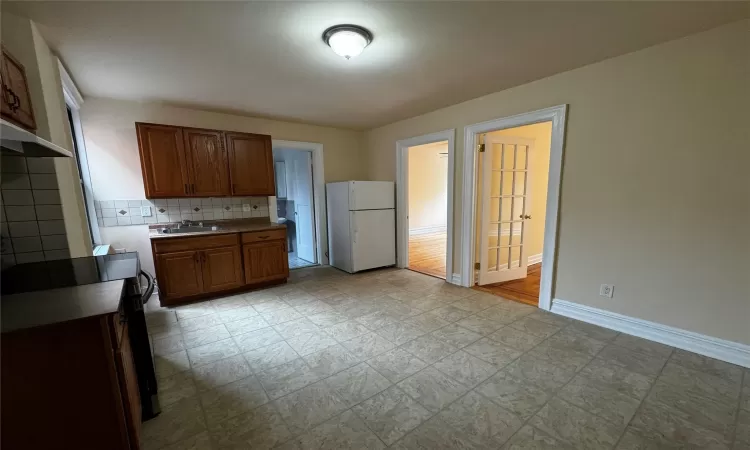 Kitchen with stove, white fridge, tasteful backsplash, and sink