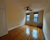 Unfurnished room featuring ceiling fan, radiator heating unit, and light wood-type flooring