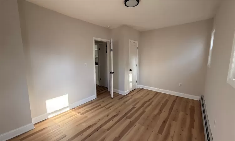 Unfurnished room with a baseboard radiator and light wood-type flooring