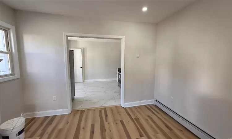 Spare room with a baseboard radiator and light hardwood / wood-style floors