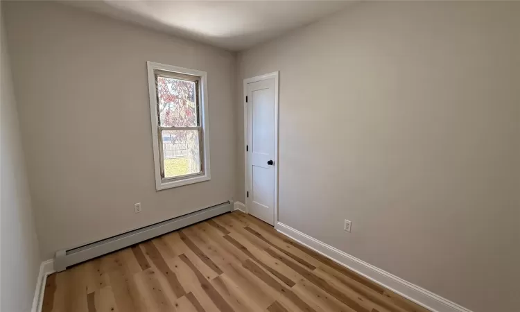 Spare room with light wood-type flooring and a baseboard radiator