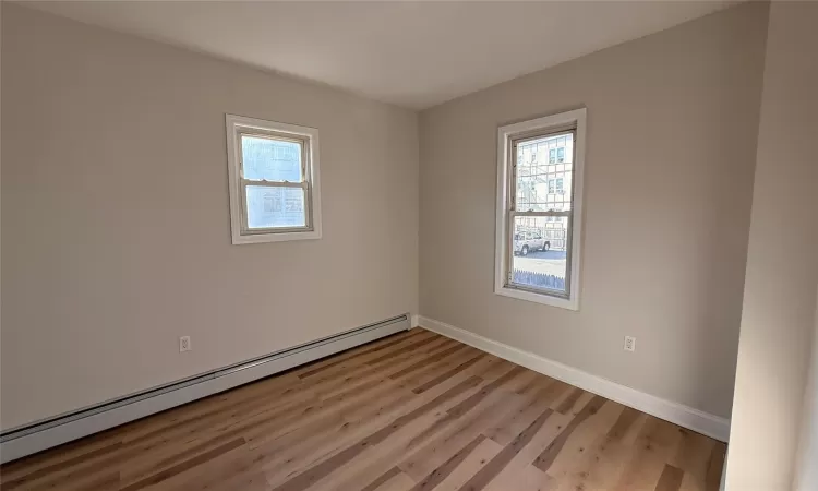 Empty room featuring light hardwood / wood-style flooring and a baseboard heating unit