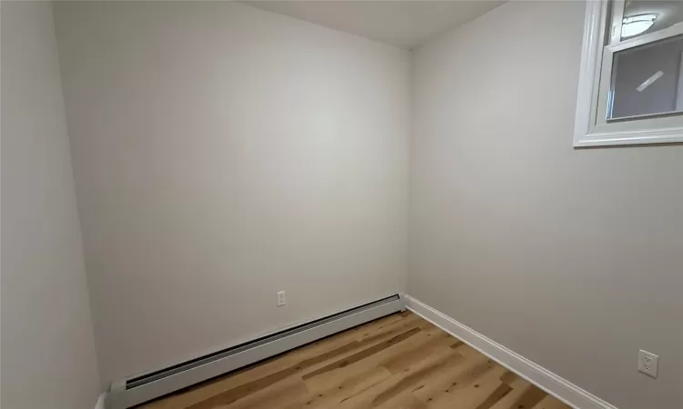 Empty room featuring hardwood / wood-style floors and a baseboard radiator