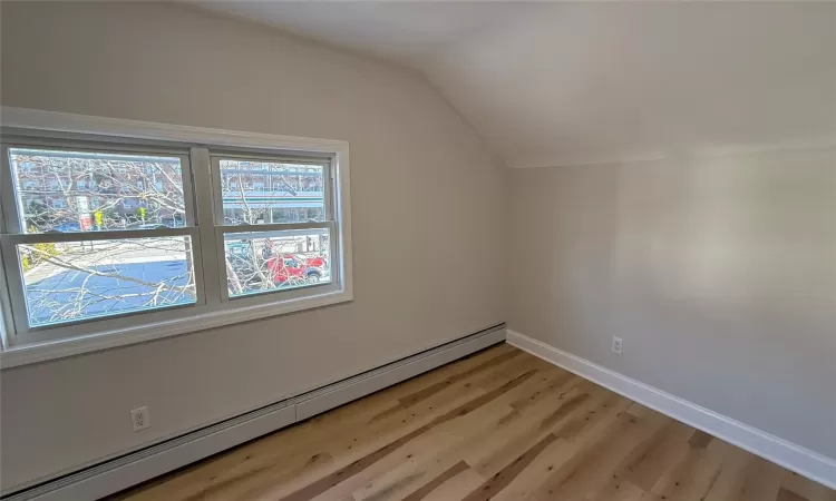 Bonus room featuring light hardwood / wood-style floors, vaulted ceiling, and a baseboard heating unit