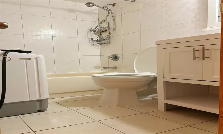 Bathroom with tile patterned floors,  shower combination, tile walls, and toilet