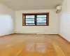 Empty room with a wall mounted AC, light hardwood / wood-style flooring, and a baseboard heating unit