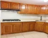 Kitchen with sink, stainless steel gas cooktop, tasteful backsplash, range hood, and light tile patterned flooring