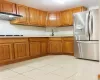 Kitchen with stainless steel fridge, light tile patterned floors, tasteful backsplash, cooktop, and extractor fan