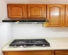 Kitchen with gas stovetop, tasteful backsplash, and wall chimney range hood