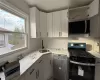 Kitchen featuring white cabinets, sink, light stone countertops, and stainless steel appliances