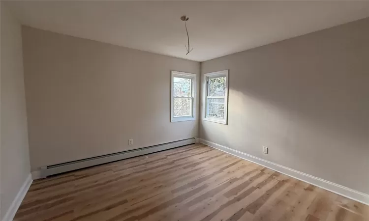 Empty room featuring a baseboard radiator and hardwood / wood-style flooring