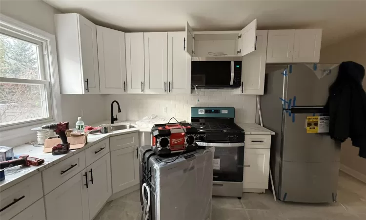 Kitchen with white cabinetry, sink, and stainless steel appliances