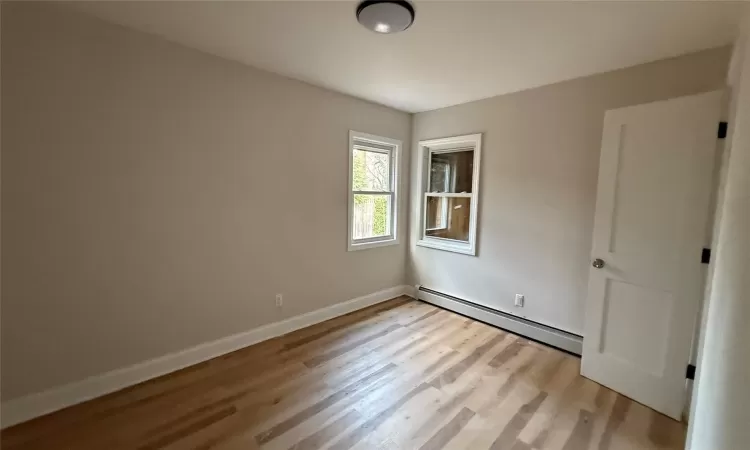 Empty room with light hardwood / wood-style flooring and a baseboard radiator