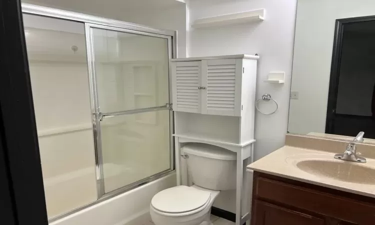 Full bathroom featuring shower / bath combination with glass door, vanity, and toilet