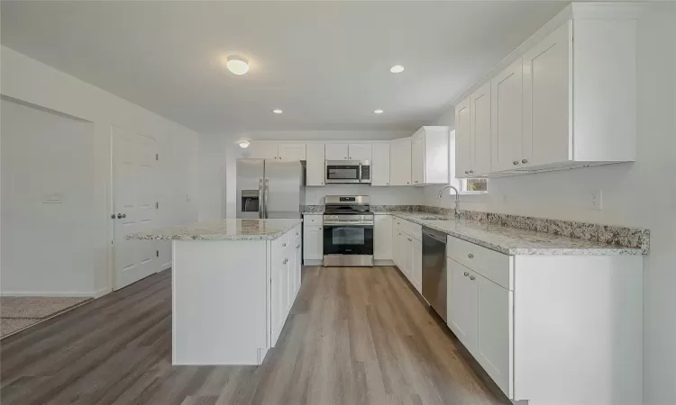 Kitchen with light stone countertops matching the white cabinets.