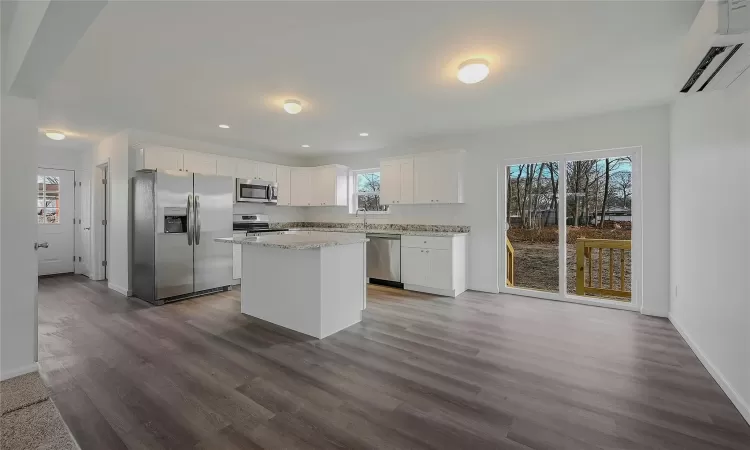 Kitchen with a center island, soft close white cabinets & complete stainless kitchen appliances.