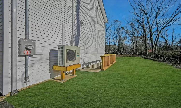 View of side of property with a yard and ac unit with walk down to full unfinished basement.