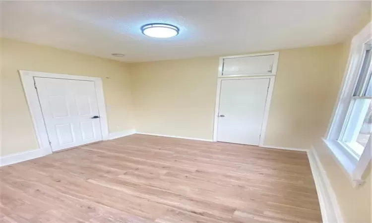 Unfurnished room with a textured ceiling and light wood-type flooring