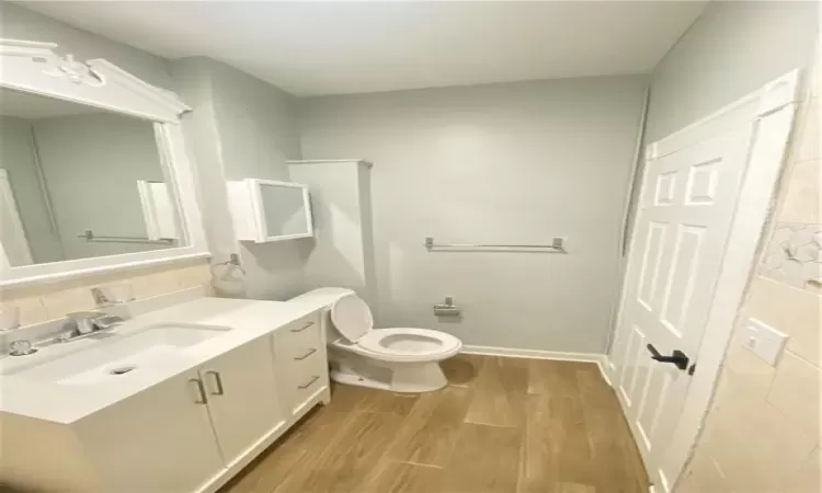 Bathroom with tasteful backsplash, toilet, vanity, and hardwood / wood-style flooring