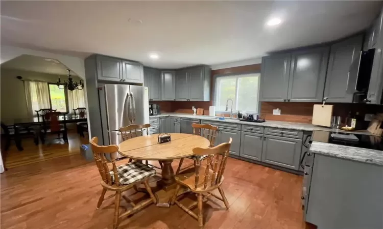 Kitchen featuring appliances with stainless steel finishes, a chandelier, light hardwood / wood-style floors, and gray cabinetry