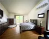 Bedroom featuring access to outside, light hardwood / wood-style flooring, a wall mounted air conditioner, and lofted ceiling