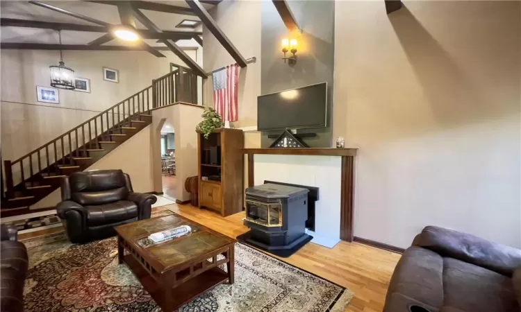 Living room with a high ceiling, hardwood / wood-style floors, and a wood stove