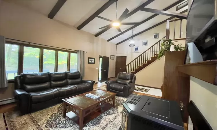 Living room with beamed ceiling, baseboard heating, ceiling fan, and high vaulted ceiling