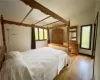 Bedroom with multiple windows, lofted ceiling, and light wood-type flooring