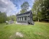 Rear view of house featuring a lawn and a storage unit