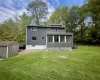 Back of house featuring a sunroom, a lawn, and a storage unit