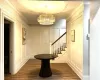 Corridor featuring a notable chandelier, crown molding, and dark wood-type flooring