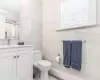 Bathroom with vanity, crown molding, tile walls, hardwood / wood-style floors, and toilet