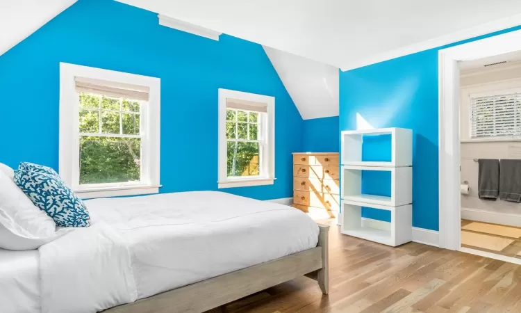 Bedroom featuring multiple windows, crown molding, light hardwood / wood-style flooring, and lofted ceiling