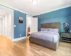 Bedroom with ensuite bathroom, light hardwood / wood-style floors, and ornamental molding