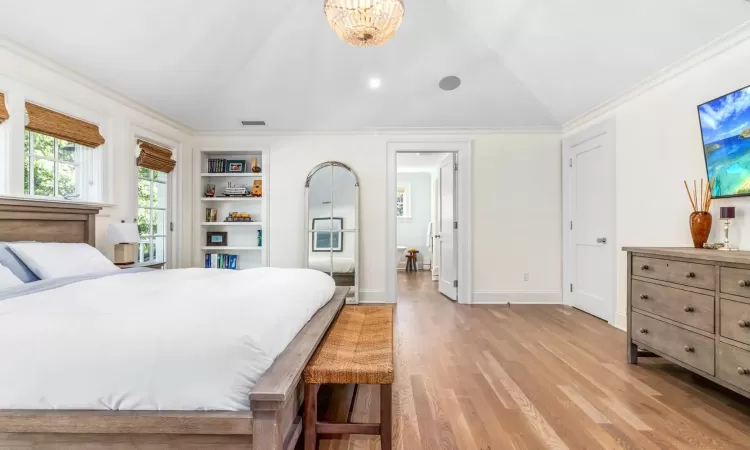 Bedroom with light hardwood / wood-style flooring, a notable chandelier, lofted ceiling, and crown molding